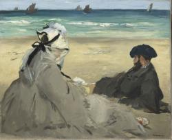 une femme et un homme, assis, de dos sur une plage regardant la mer